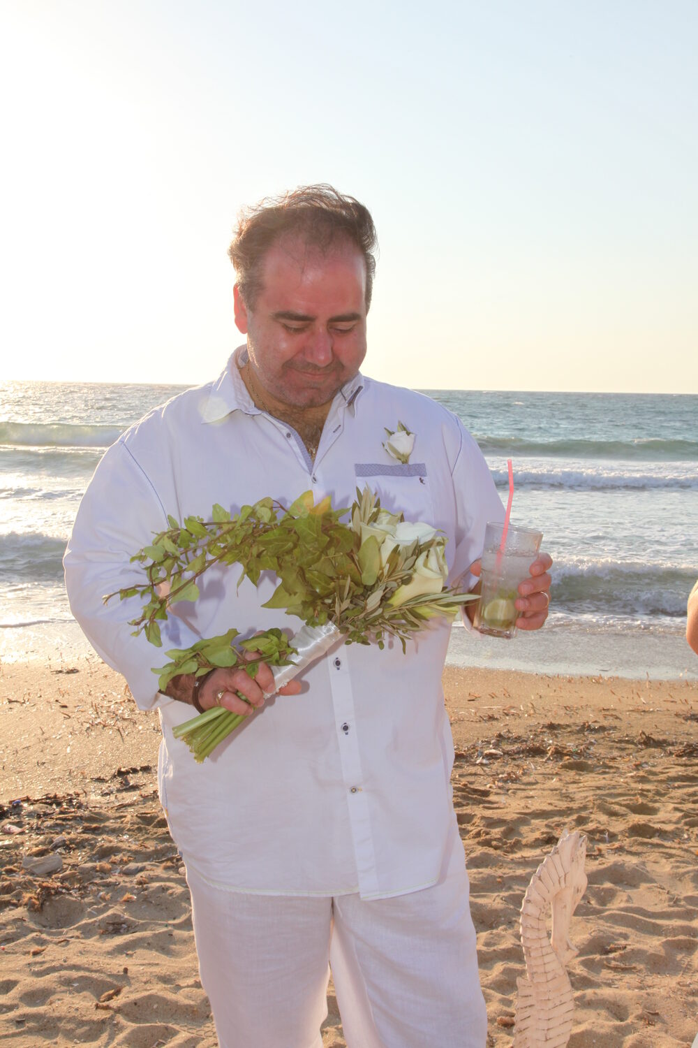 The groom holding the bouquet on the beach