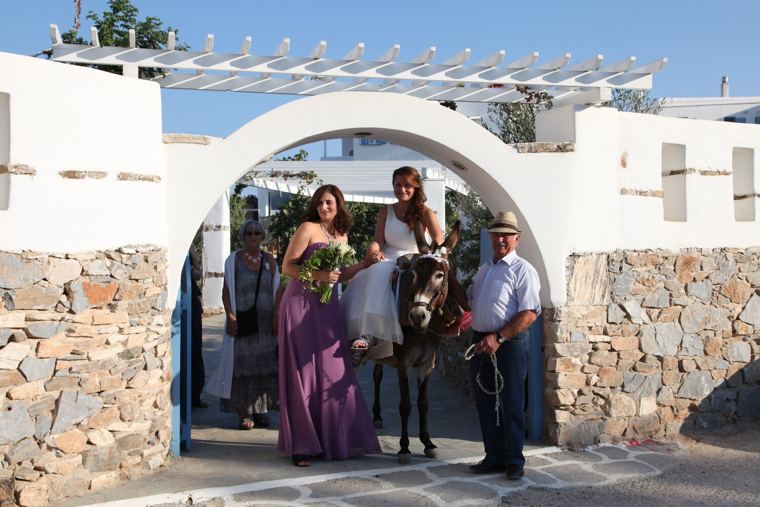 The bride riding through the arch on a donkey