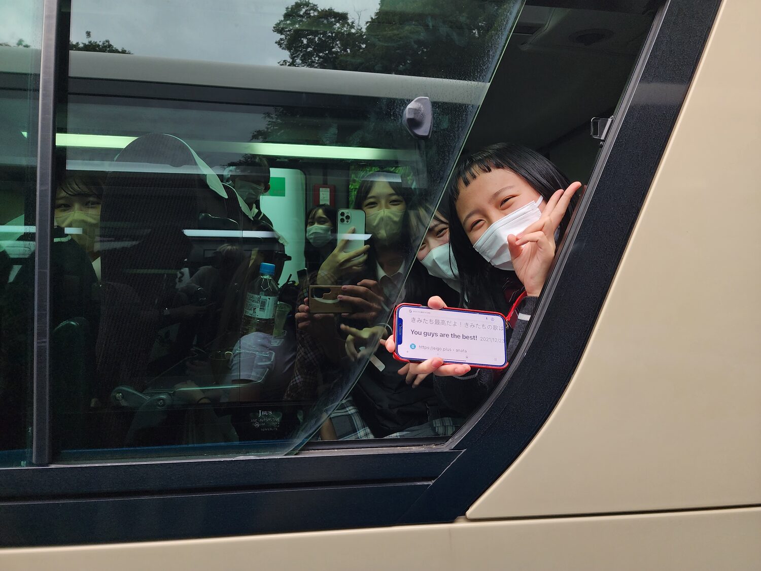 Japanese schoolgirls smiling from a bus window