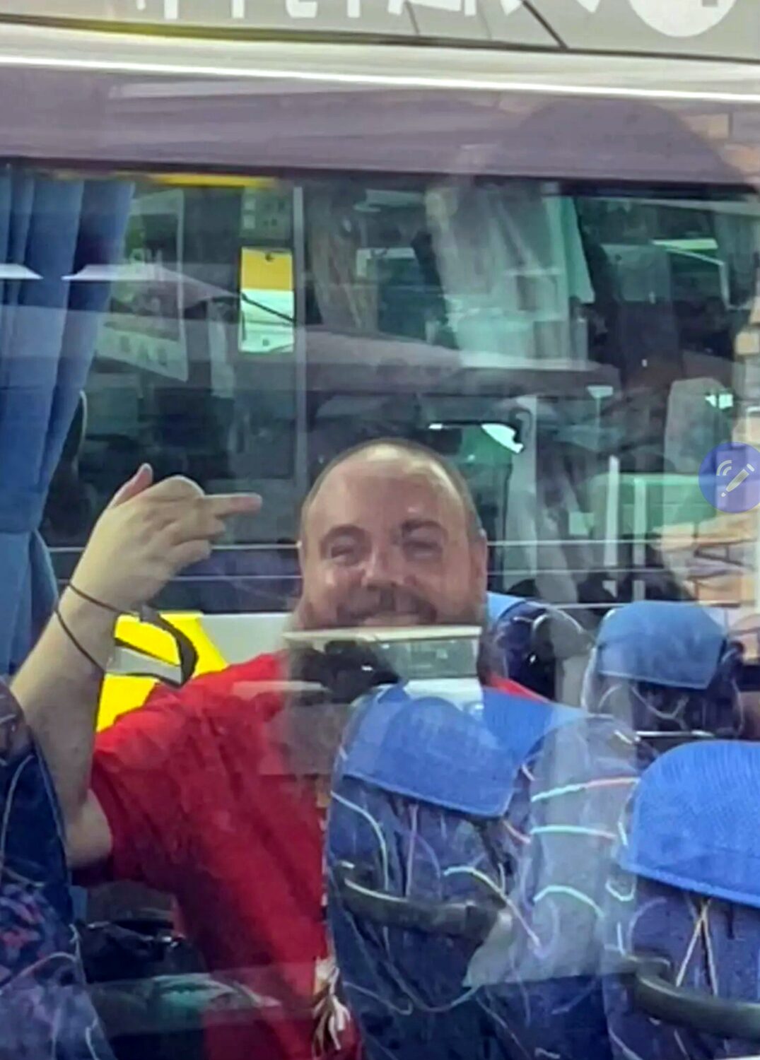 A man waving from a bus window