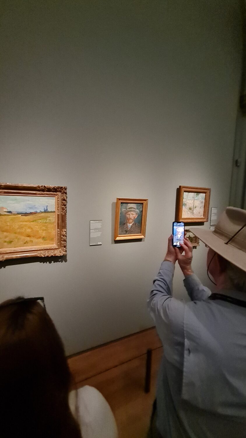 A visitor photographing a painting